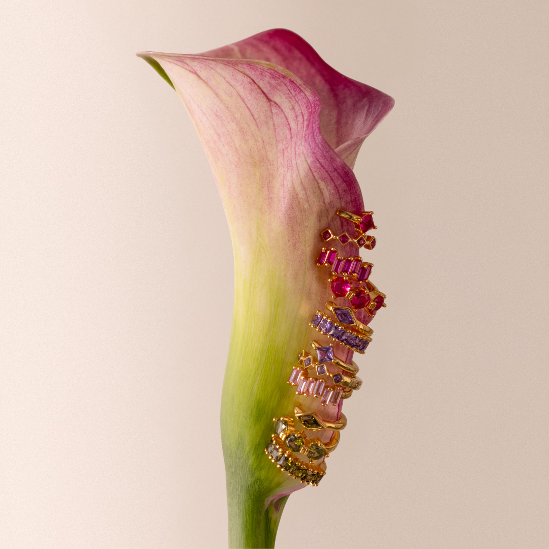 Flatlay image of diamond earrings clipped onto fruits, laid on top of a vintage floral wallpaper background