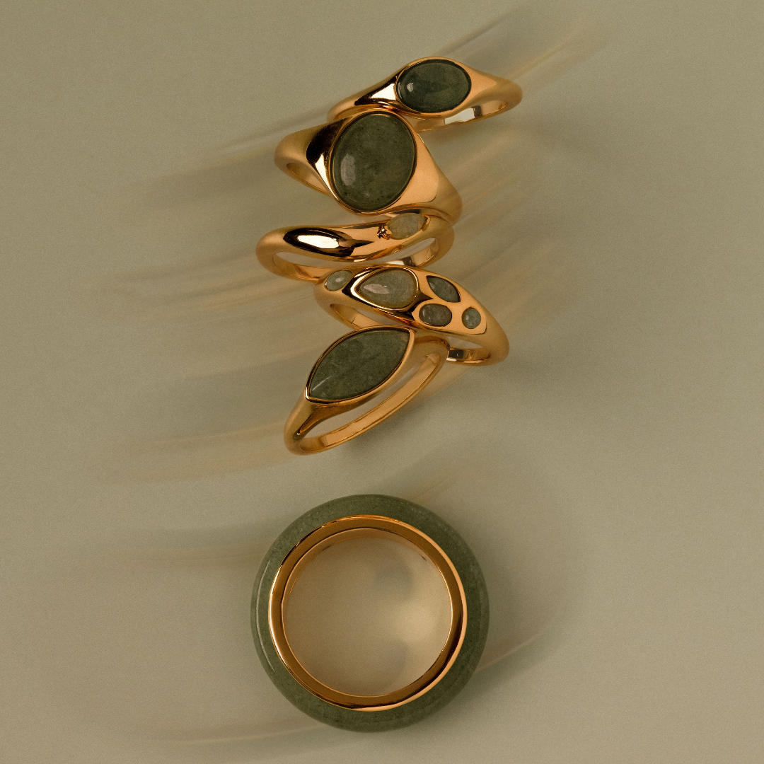 Flatlay of Jade gemstone rings against a green background
