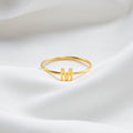 Gold ring with letter 'M' on a white satin background