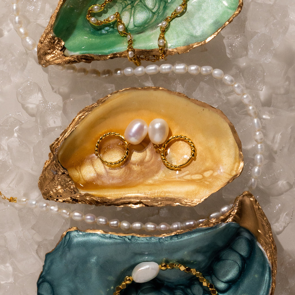 Twisted Pearl Hoops displayed on colorful oyster shells and crushed ice.