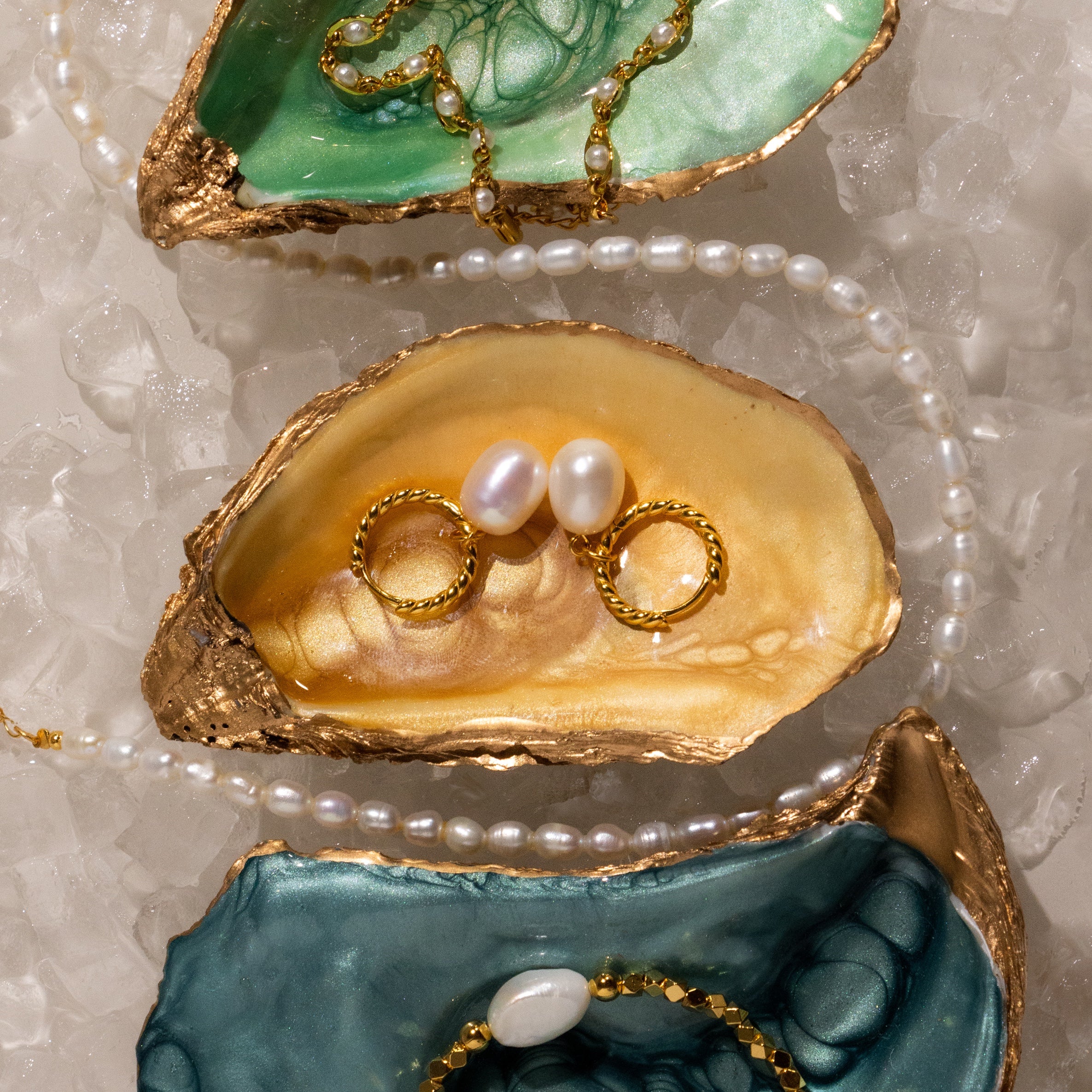 Twisted Pearl Hoops displayed on colorful oyster shells and crushed ice.