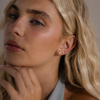 Close-up of a woman with long blonde hair wearing Opal Cluster Flatback Studs in 18K Gold, touching her chin—perfect for adding a touch of elegance to any ear stack.