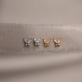 Gold and silver butterfly-shaped earrings on a beige fabric background