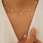 Close-up of the Forever Pave Heart Necklace, featuring sparkling heart and flower charms, styled on a white top—perfect for bridal jewelry or special occasions.