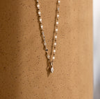 The Dainty Marquise Pendant Necklace is shown against a speckled beige background.