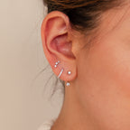 Close-up of an ear with multiple piercings, each adorned with the Diamond Earrings Set in Sterling Silver, featuring sparkling huggie hoops and dainty studs.