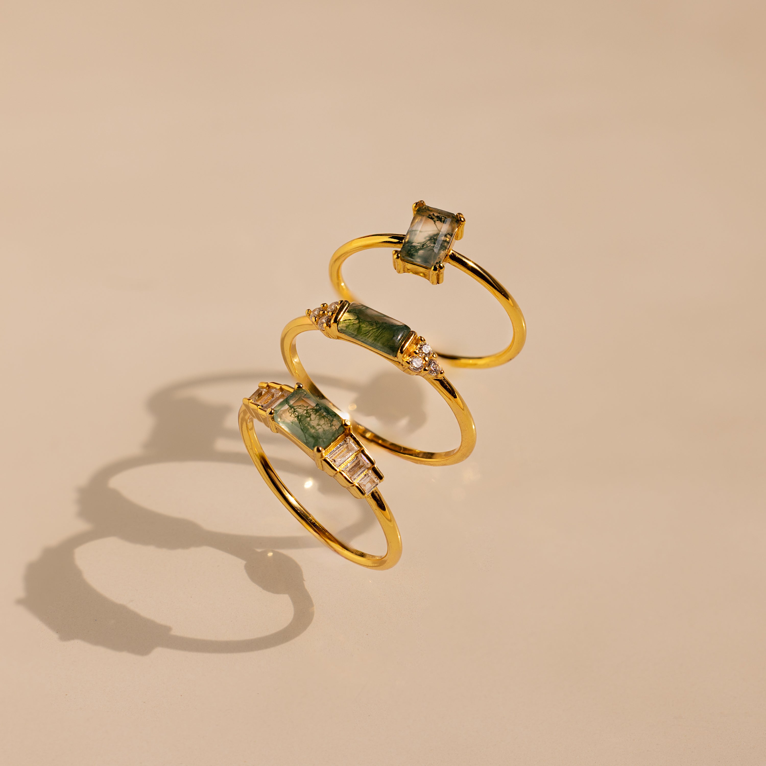 Three Agate Statement Rings with green agate gemstones stand upright on a neutral background, casting soft shadows—an eye-catching display of the Agate Statement Ring collection.