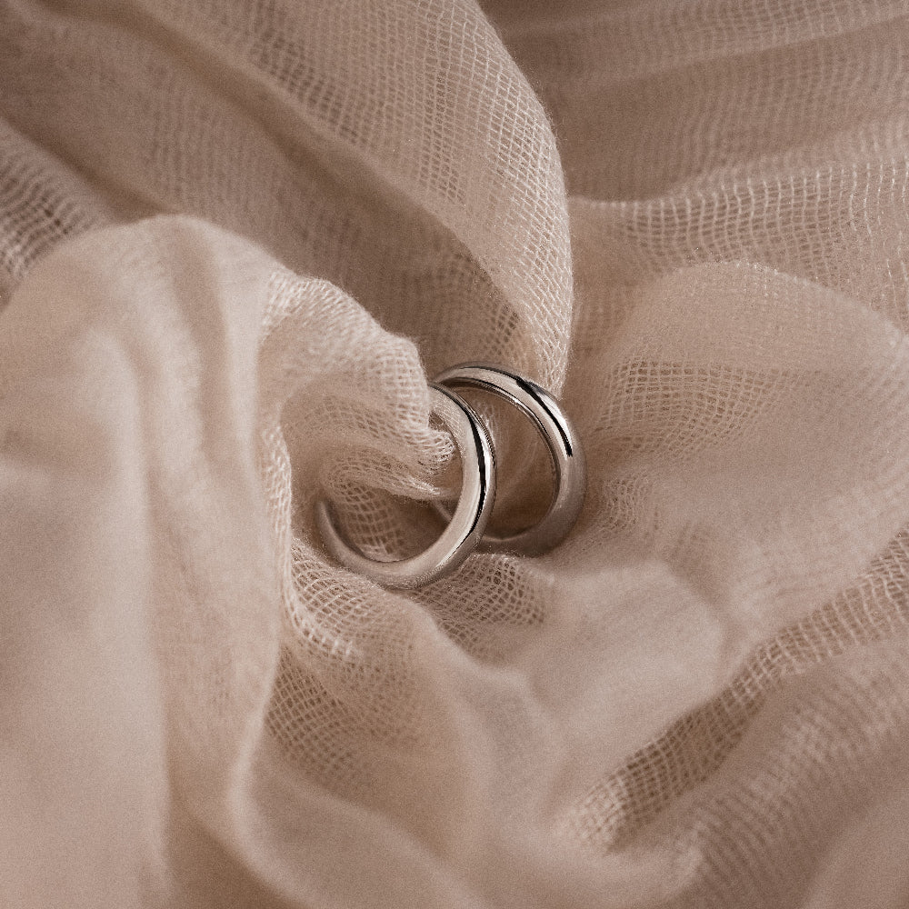 Silver cuff earrings on a beige fabric background