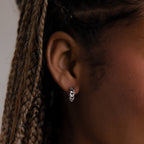 Close-up of a model wearing a silver chain hoop earring with braided hair.