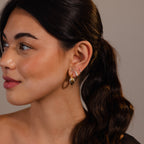 Woman with long dark hair in a ponytail wears Twisted Mixed Metal Hoops, looking to the left.