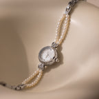 Beaded Pearl Timepiece in Sterling Silver displayed on a smooth, cream-colored curved surface.