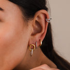 Close-up of a person's ear wearing Twisted Link Earrings in Mixed Metal, showcasing modern gold and silver hoops, an ear cuff, and sculptural jewelry accents.