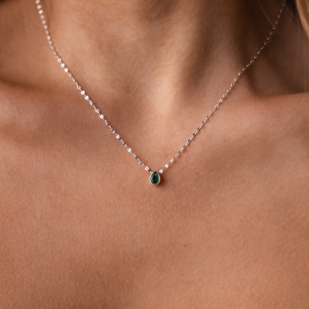 The Multiple Teardrop Birthstone Necklace in Sterling Silver features elegant green teardrop pendants that rest gracefully on a woman's neck, making it a beautiful piece of keepsake jewelry.
