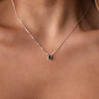 The Multiple Teardrop Birthstone Necklace in Sterling Silver features elegant green teardrop pendants that rest gracefully on a woman's neck, making it a beautiful piece of keepsake jewelry.