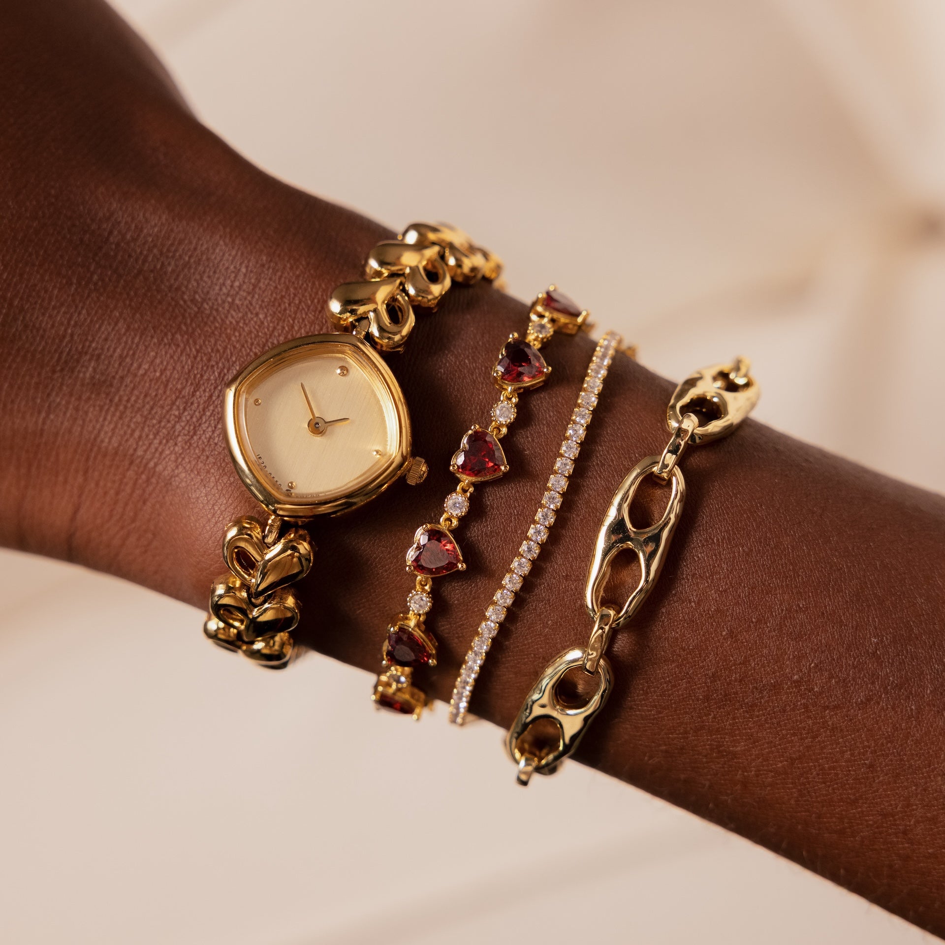 A wrist adorned with the Organic Mariner Chain Bracelet and gold watch, set against a soft beige background, highlights the allure of contemporary jewelry.