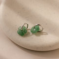 Jade Flower Hoops in Silver, featuring delicate jade flower charms, rest on a speckled beige ceramic dish—perfect for lovers of dainty earrings.
