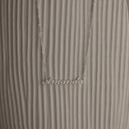 Silver necklace with 'Amanda' pendant on a textured white surface