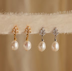 Two pairs of Pearl Diamond Drop Earrings in 18K Gold are displayed on a textured beige fabric.