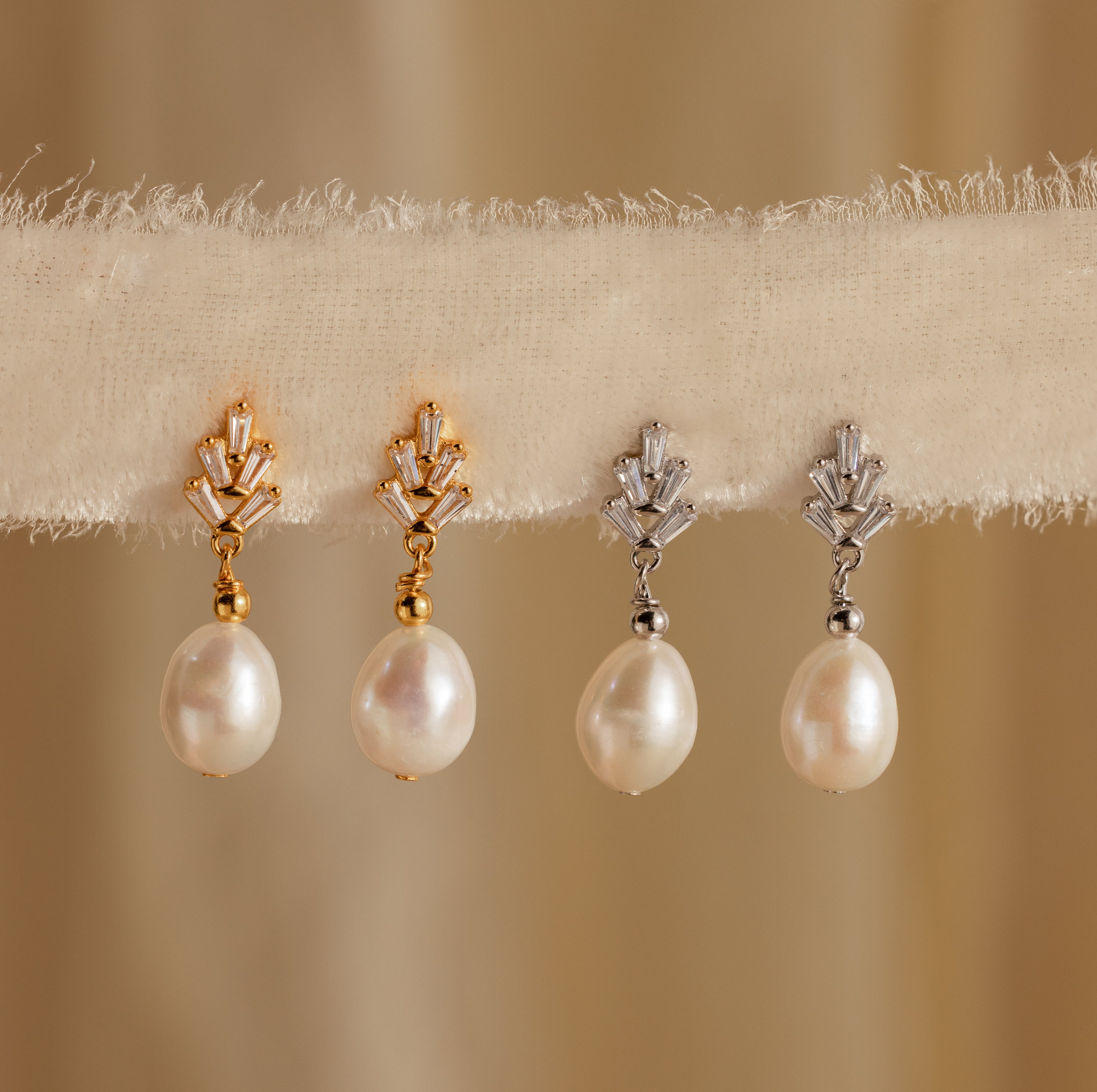 Two pairs of vintage-inspired Pearl Diamond Drop Earrings in Silver, hanging on a fabric strip.