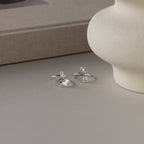 Displayed near a vase and book, the Duo Pet Initial Wrap Ring in Sterling Silver features elegant letter charms—making it the perfect personalized pet ring for any animal lover.