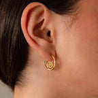 A close-up of an ear wearing a small, gold Spiral Swirl Hoops earring—ideal for beach lovers and boho vacation styles.