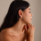 Woman with long dark hair wears Spiral Swirl Hoops in Silver, seen in profile with hands gently clasped—perfect boho jewelry for your next vacation.