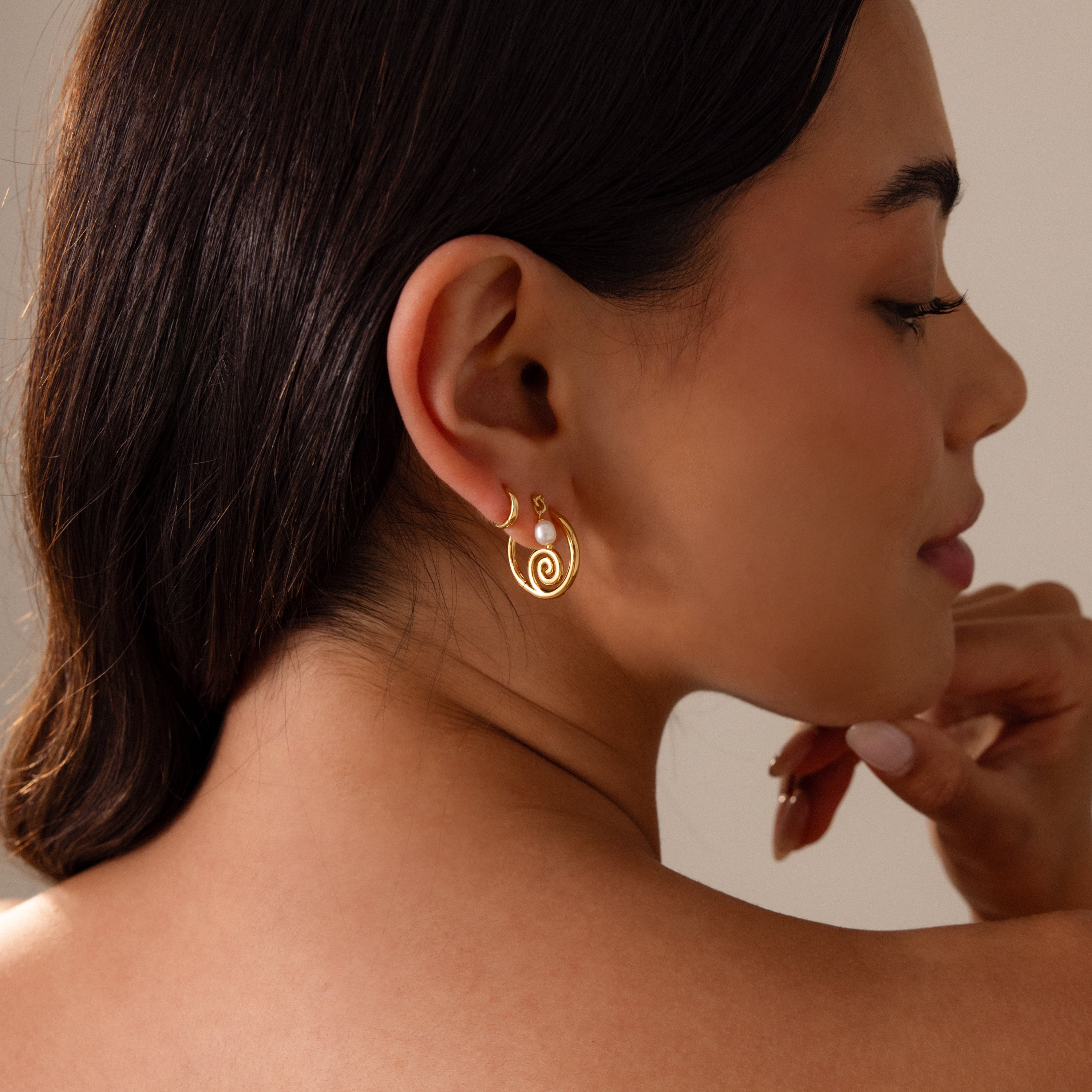 Woman with dark hair wearing Spiral Swirl Hoops in Silver, posing in profile with a soft smile—perfect boho vacation jewelry for a relaxed, beachy vibe.
