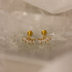 The Marquise Diamond Climbers in 18K Gold feature small, leaf-shaped clear stones—an elegant choice for wedding jewelry, shown on a light, textured surface.