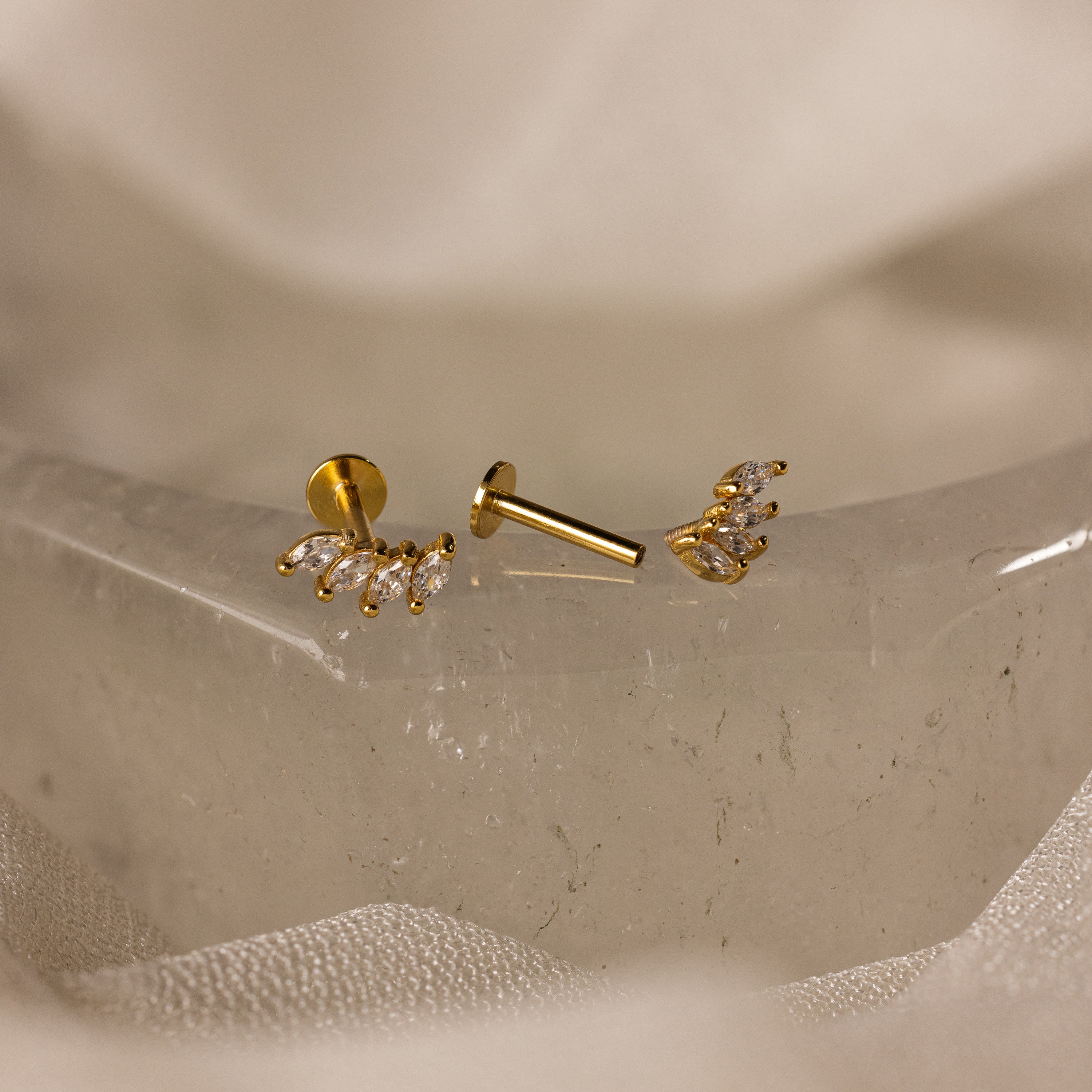 Marquise Diamond Climbers in 18K Gold, featuring elegant diamond studs, perfect for wedding jewelry, displayed on a textured, translucent surface.