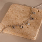 Heart Charm Bracelet in Sterling Silver, featuring delicate heart charms and displayed on a textured beige stone—a thoughtful gift for your girlfriend.