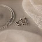 The Marquise Diamond Climbers in Silver—elegant stud earrings with sparkling stones, ideal for wedding jewelry—are showcased on a light beige fabric background.