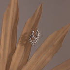 Beaded Hoops in Sterling Silver with small beads hang delicately on dried brown leaves, their textured shine standing out against a neutral background.