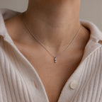 The Pearl Diamond Drop Necklace in Silver adds elegance when styled over a cream ribbed buttoned sweater.