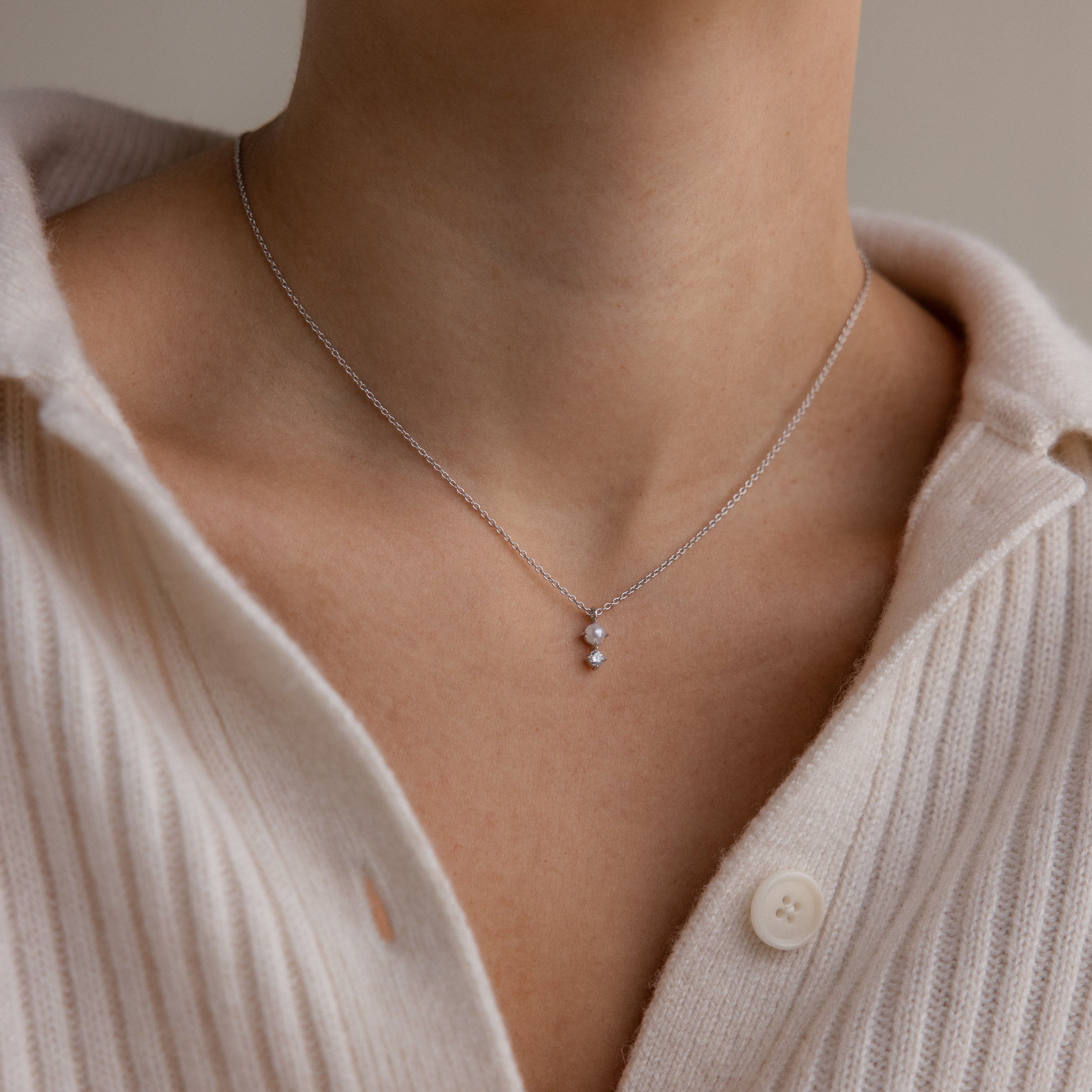 The Pearl Diamond Drop Necklace in Silver adds elegance when styled over a cream ribbed buttoned sweater.