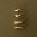 The Mixed Metal Diamond Curve Ring Set, featuring four stacked rings with diamond accents, is displayed vertically against an olive green background.