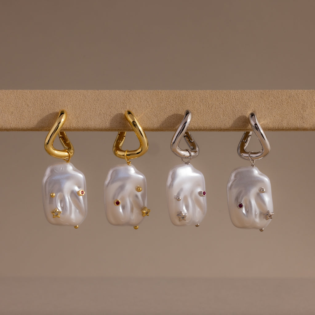 The Celestial Baroque Pearl Charm Hoops in 18K Gold feature abstract faces, gemstone accents, and a mix of gold and silver hooks—a unique twist on classic pearl hoop earrings.