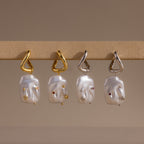 The Celestial Baroque Pearl Charm Hoops in 18K Gold feature abstract faces, gemstone accents, and a mix of gold and silver hooks—a unique twist on classic pearl hoop earrings.
