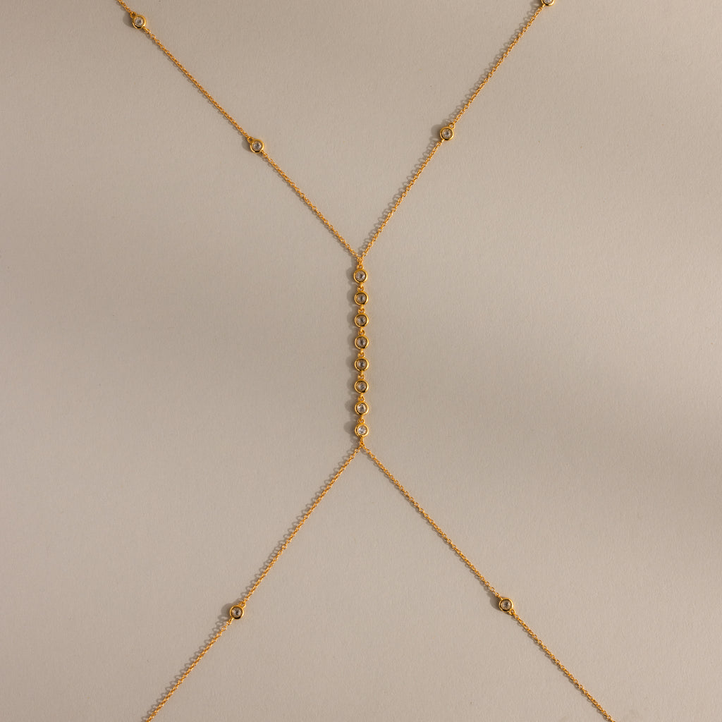 Isolated flat lay of the gold Sprinkle Diamond Body Chain on a neutral background, showing its full design and detailing.