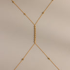 Isolated flat lay of the gold Sprinkle Diamond Body Chain on a neutral background, showing its full design and detailing.
