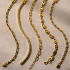 Five gold bracelets with unique designs arranged in wavy lines on a light beige surface—the Corporate Gift Box offers a stunning selection of curated jewelry, ideal for any special occasion.