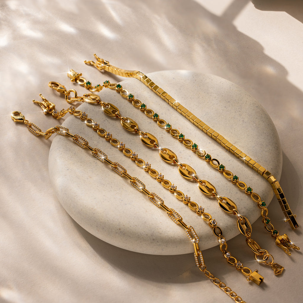 The Cube Bracelet: a bold mens statement piece with geometric bead links and green and clear gemstones, displayed on stone under soft sunlight for a modern look.