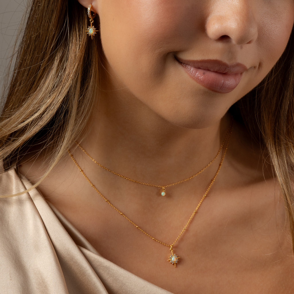 Close-up of a woman wearing the Opal Star Necklace & Earrings Set in 18K Gold, featuring delicate gold chains and opal star pendants.
