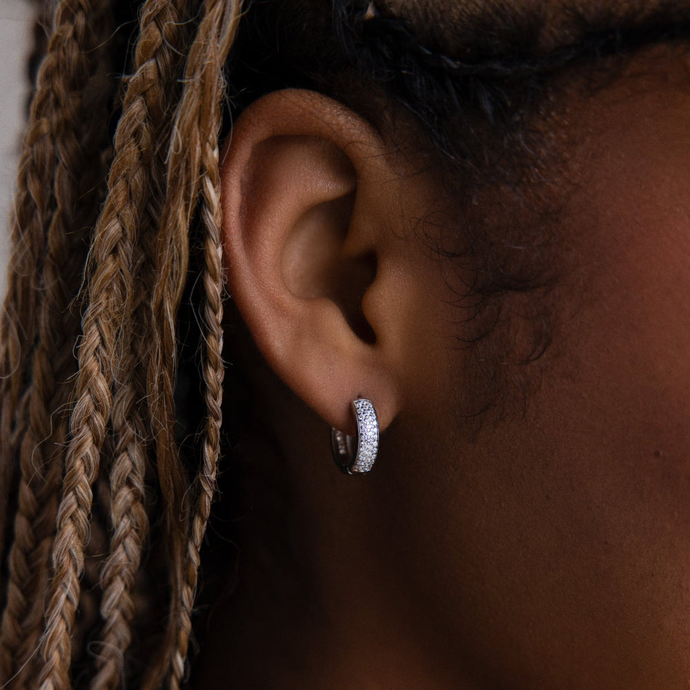 Close-up of an ear with a diamond hoop earring and braided hair.