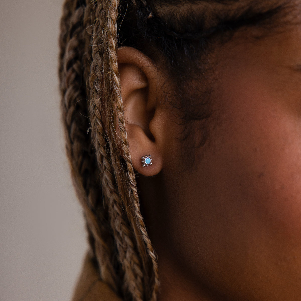 Close up of a model wearing dainty turquoise stud earrings with a detailed silver setting, styled as everyday minimalist jewelry for a subtle pop of color.