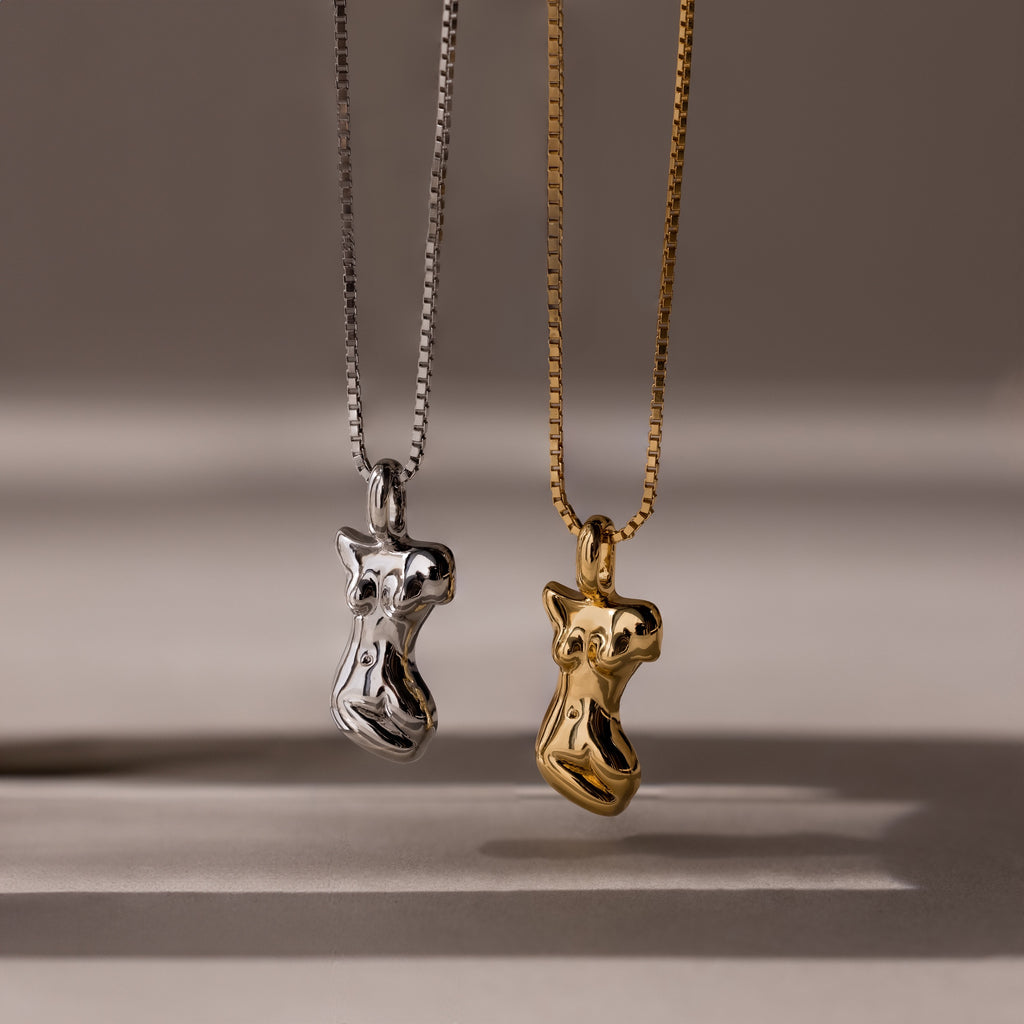 The Kinn Body Necklace features two abstract female torso shaped pendants—one silver, one gold—making a bold statement piece for anyone who loves standout jewelry.