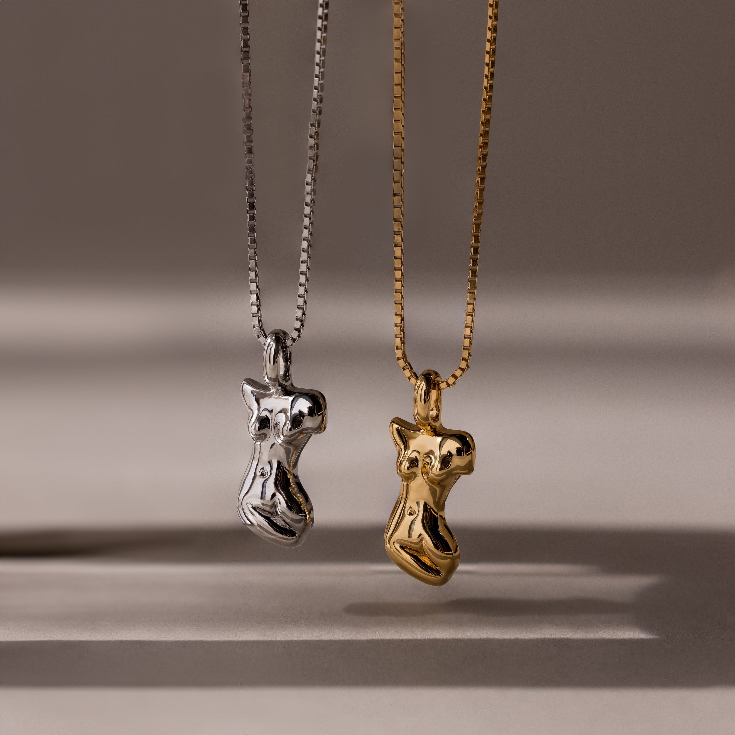 The Kinn Body Necklace features two abstract female torso shaped pendants—one silver, one gold—making a bold statement piece for anyone who loves standout jewelry.