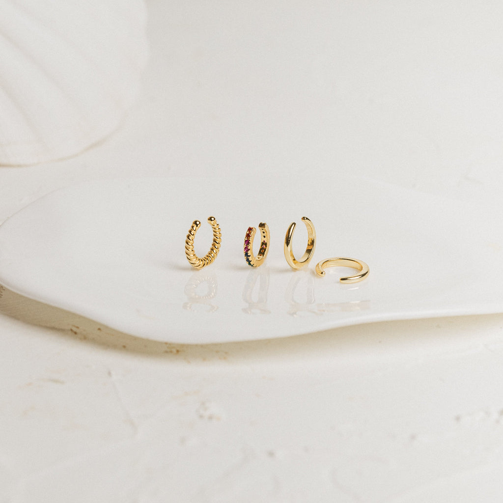 Set of various gold cuff earrings on a white surface