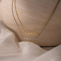A gold and a silver script Mrs. necklace rest on a white textured surface—an ideal gift for the bride-to-be before she officially becomes a Mrs.
