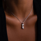 A person wearing the Kinn Body Necklace, featuring a small body-shaped pendant, against their bare skin.