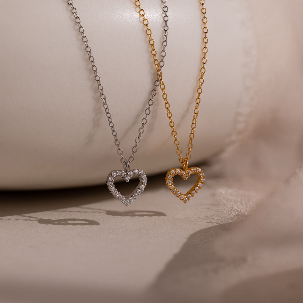 The Forever Pave Heart Necklaces are shown with two heart-shaped pendants—one silver, one gold—with sparkling stones, perfect for bridal jewelry or special occasions.